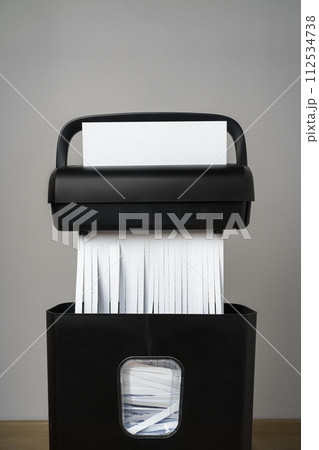 Black paper shredder cutting paper on gray background 112534738