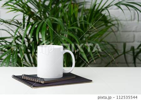Coffee mug on table against brick wall 112535544