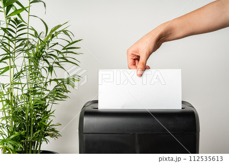 Black paper shredder cutting paper on gray background Black paper shredder cutting paper on gray background 112535613