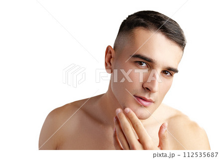 Young attractive brunet guy with perfect skin touching chin on white background Young attractive brunet guy with perfect skin touching chin on white background 112535687