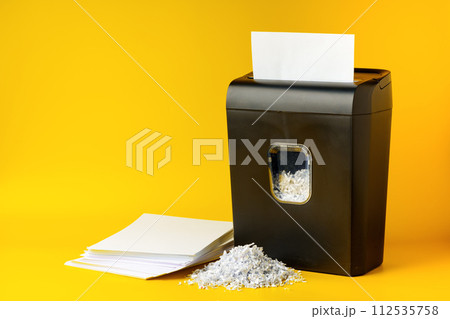 Office paper shredder on yellow studio background 112535758