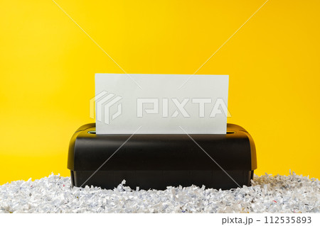 Office paper shredder on yellow studio background Office paper shredder on yellow studio background 112535893