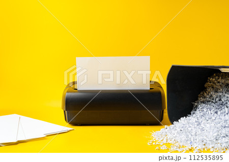 Office paper shredder on yellow studio background 112535895