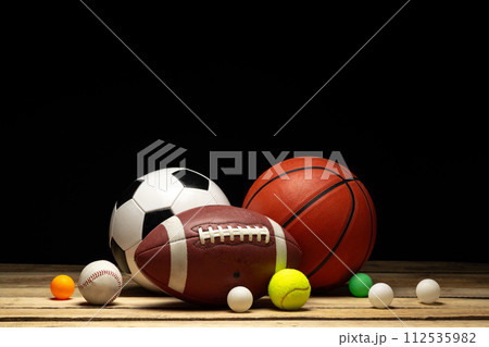 Set of various sport balls on wooden floor on black background 112535982