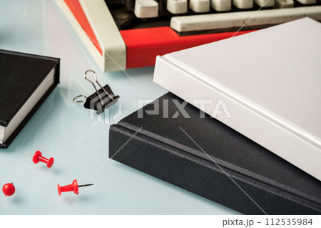 Hardcover book and vintage typewriter on white desk 112535984
