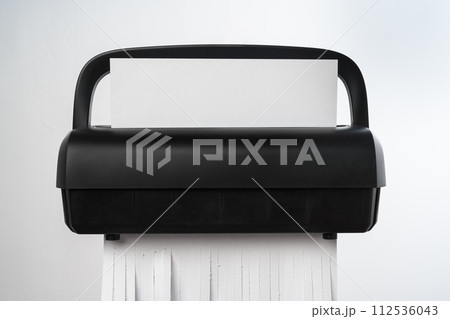 Black paper shredder cutting paper on gray background Black paper shredder cutting paper on gray background 112536043