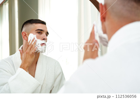 Reflection of a young man shaving in bathroom mirror close up Reflection of a young man shaving in bathroom mirror close up 112536056