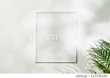 White wooden photo frame with plant leaves on white background 112536260