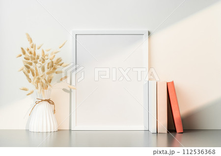 Blank picture frame and dried flower in a vase on white background 112536368