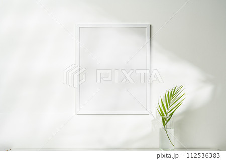 White wooden photo frame with plant leaves on white background 112536383