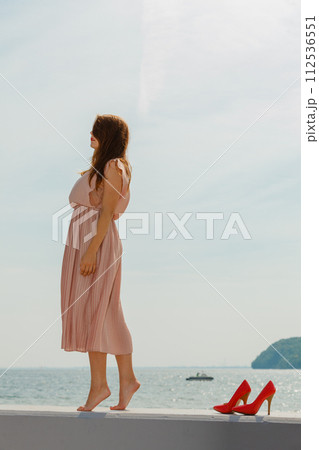Woman wearing long light pink dress on jetty 112536551