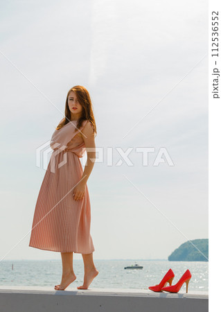 Woman wearing long light pink dress on jetty 112536552