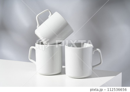 White ceramic mugs on gray background with shadows White ceramic mugs on gray background with shadows 112536656