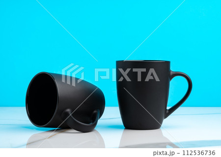 Two ceramic mugs on blue studio background Two ceramic mugs on blue studio background 112536736