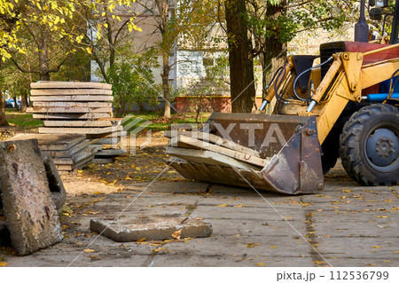 Excavator bulldozer loads old concrete slabs on road repair 112536799
