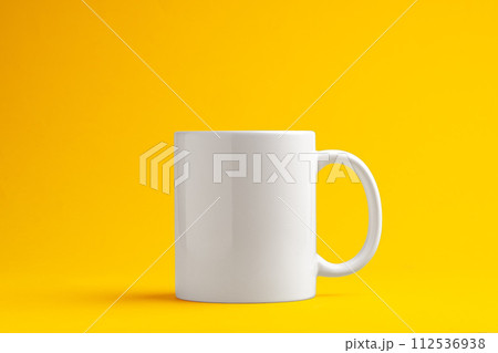 Ceramic mug on yellow studio background close up Ceramic mug on yellow studio background close up 112536938