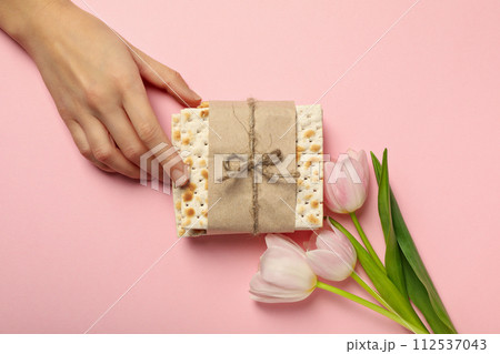 Matzo, hand and flowers on pink background, top view 112537043