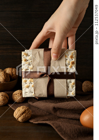 Matzo in hand, nuts and egg on wooden background Matzo in hand, nuts and egg on wooden background 112537049