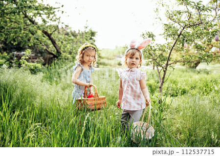 Easter egg hunt. Group Of Children Wearing Bunny Ears Running To Pick Up colorful Egg On Easter Egg Hunt In Garden. Easter tradition 112537715