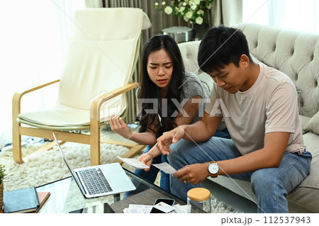 Serious young married couple checking their domestic bills and calculating family budget at home Serious young married couple checking their domestic bills and calculating family budget at home 112537943