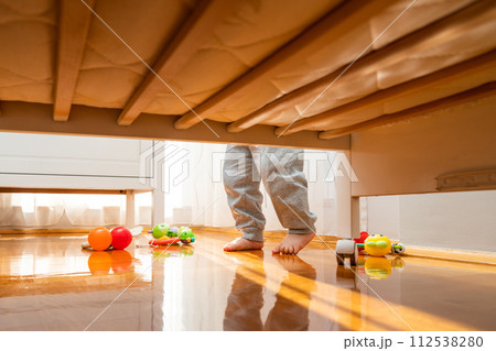 Bare feet of a baby standing in a nursery surrounded by toys Bare feet of a baby standing in a nursery surrounded by toys 112538280