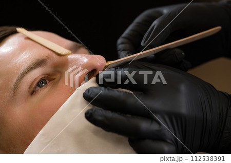 Hair removal procedure in a barbershop. Nose hair wax removal. Hair removal procedure in a barbershop. Nose hair wax removal. 112538391