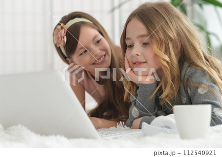 Two cute little girls with a laptop Two cute little girls with a laptop 112540921