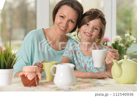 Happy mom and daughter drinking tea at home 112540936