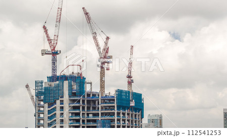 Working crane on a modern office building under construction against cloudy sky in Singapore timelapse. Working crane on a modern office building under construction against cloudy sky in Singapore timelapse. 112541253