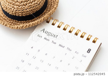 8月のカレンダーと麦わら帽子 112542045