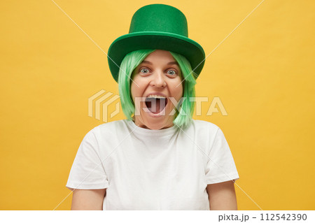Overjoyed excited amazed beautiful woman with green hair wearing leprechaun hat standing isolated over yellow background screaming wow OMG with happy face Overjoyed excited amazed beautiful woman with green hair wearing leprechaun hat standing isolated over yellow background screaming wow OMG with happy face 112542390