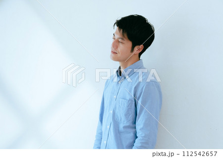 白壁を背景に立つ男性 112542657