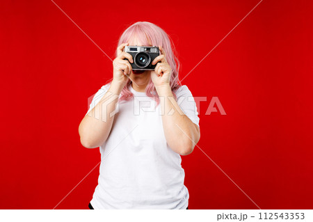 Young 30s photographer with pink hair is taking a photo isolated over red background. Home hobby, lifestyle, travel, people concept 112543353