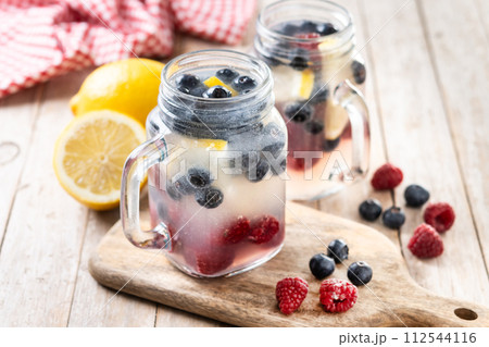 Fresh berry drink with blueberries and raspberries and lemon on wooden table.. Fresh berry drink with blueberries and raspberries and lemon on wooden table.. 112544116