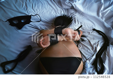 Sexy lingerie model in bdsm with a masked woman with a perfect figure wearing a belt on the bed 112546528
