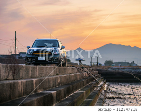 夕暮れ時の船溜まりに停車するSUV 夕暮れ時の船溜まりに停車するSUV 112547218