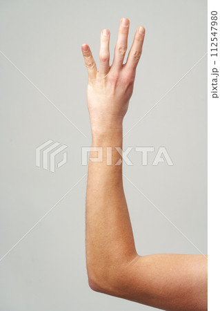 Male hand showing four fingers on gray background 112547980