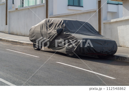 An awning covering a parked car by the side of the road. Protecting the vehicle from the harmful effects of direct hot sunlight and from the gaze of passers-by An awning covering a parked car by the side of the road. Protecting the vehicle from the harmful effects of direct hot sunlight and from the gaze of passers-by 112548862