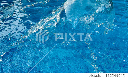 Background dynamic splash of clear water creating swirling wave in blue water with droplets suspended in motion. Clean water concept. Background dynamic splash of clear water creating swirling wave in blue water with droplets suspended in motion. Clean water concept. 112549045