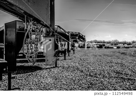 Selective focus on gooseneck trailer hitch with a row of flatbeds lined up.  112549498