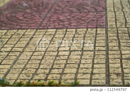 Textured surface of paving slabs running along lines, between which certain drawings are drawn. Theme of overcoming life path in which person observes various situations and gains experience Textured surface of paving slabs running along lines, between which certain drawings are drawn. Theme of overcoming life path in which person observes various situations and gains experience 112549797