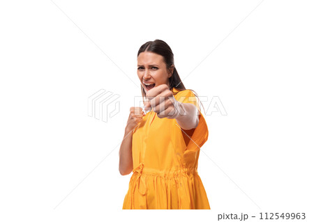 young caucasian brunette woman with long hair dressed in a yellow summer dress pulls her hand into 112549963