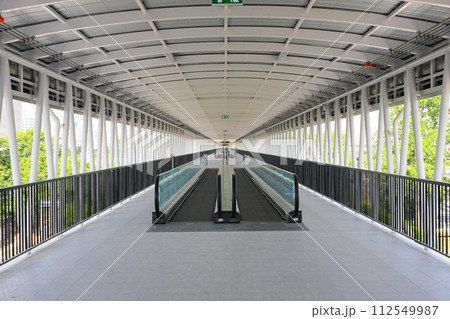 Pedestrian pathway or corridor or hallway with automatic walkway or Moving Sidewalk between train station and building. 112549987