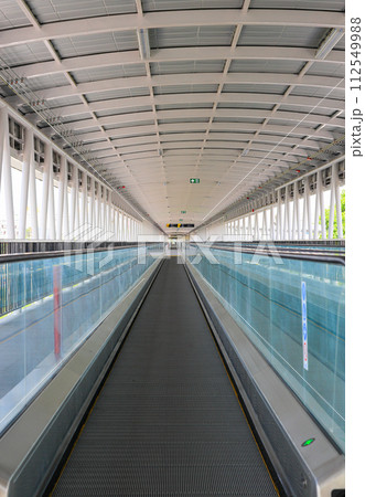 Pedestrian pathway or corridor or hallway with automatic walkway or Moving Sidewalk between train station and building. 112549988