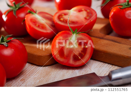 Cut fresh tomatoes on wooden table in home kitchen Cut fresh tomatoes on wooden table in home kitchen 112551765