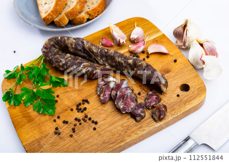 Dry-cured pork sausage on wooden chopping board Dry-cured pork sausage on wooden chopping board 112551844
