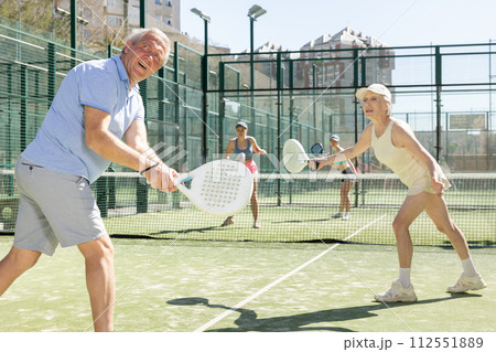 Determined sporty older husband and wife doing his best playing padel in court Determined sporty older husband and wife doing his best playing padel in court 112551889