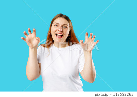 Pretty cheerful woman smiling funny and doing claw gesture as cat, aggressive and sexy expression. Studio portrait. 112552263