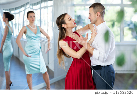 Woman in red and man in formal wear rehearsing tango in pair Woman in red and man in formal wear rehearsing tango in pair 112552526