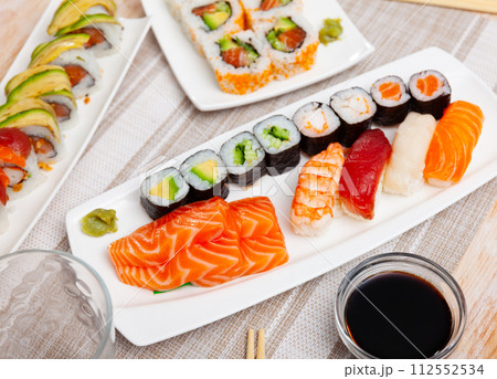 Assorted sushi rolls on plates on tabl 112552534